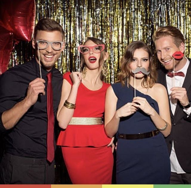 Friends posing with photo booth props in front of a gold tinsel backdrop